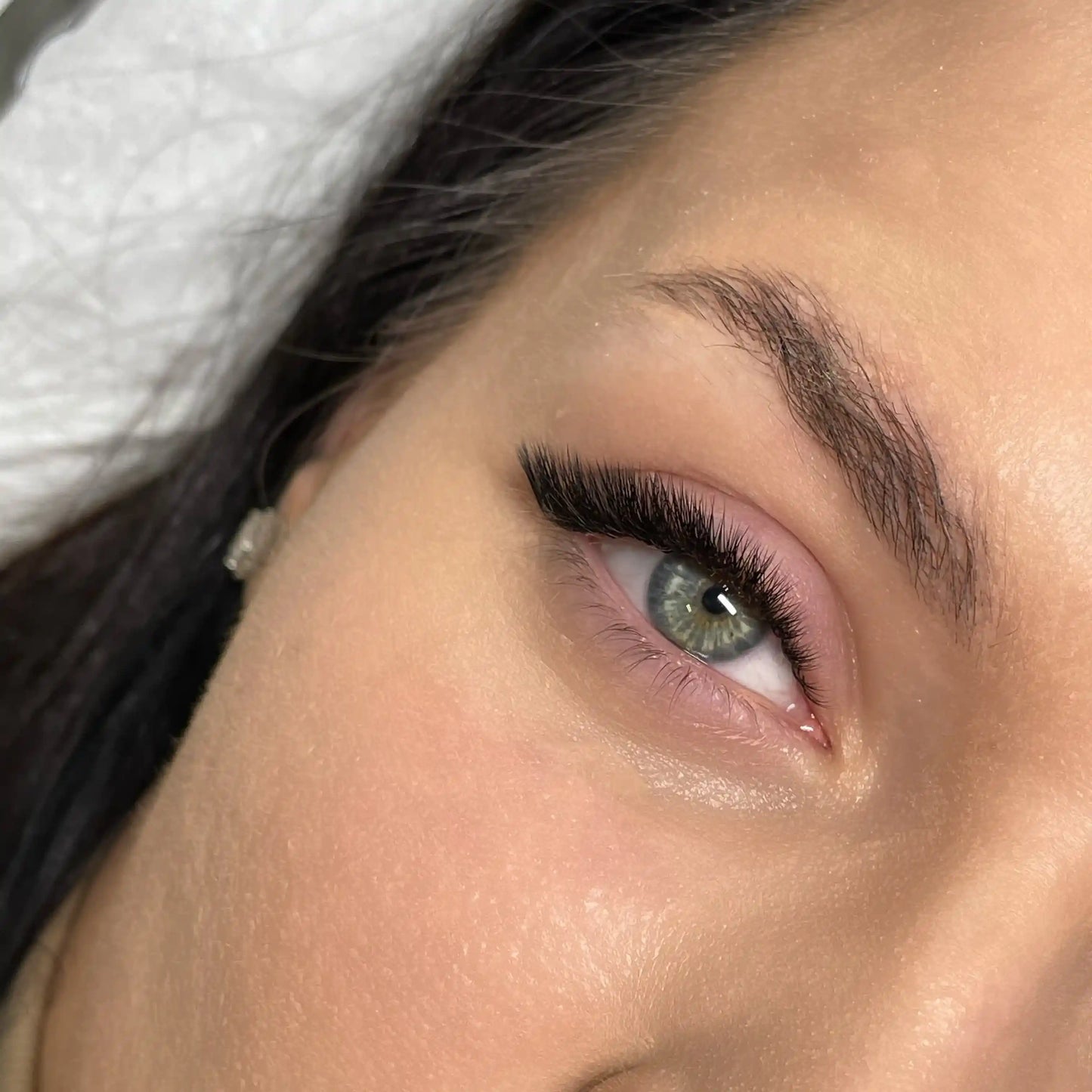Close-up of a client's green eye with Fox Eye lash extensions using L curls, showcasing lifted outer corners and seamless lash direction.