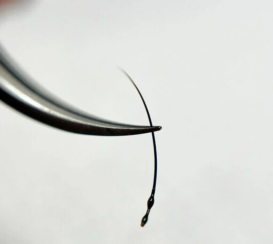Close-up of lash glue drop on extension before application for retention