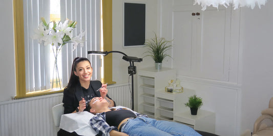 Lash technician applying eyelash extensions to a client in a professional salon setting at The Lash Box