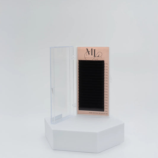 MAGIQUE black eyelash extensions tray in closed plastic case, displayed on white pedestal.
