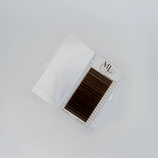 Top view of MAGIQUE Pecan brown lash tray inside open clear case, showing soft faux mink lashes in warm brown.